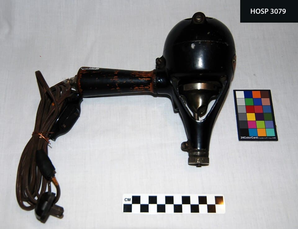 Hand held vibrator, switch & cord; Metal painted black; oval metal plate, orange with silver letters, "Shelton VibratorPatent (f4a717b6-06ed-4189-88c5-0ebdced7599c)